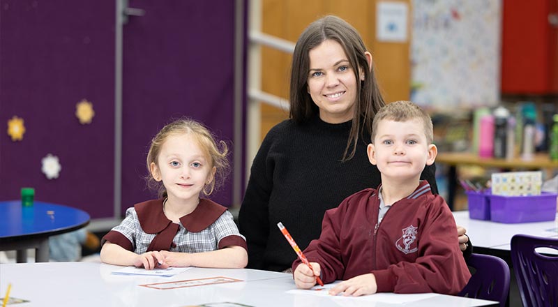 Two students being assisted by a teacher