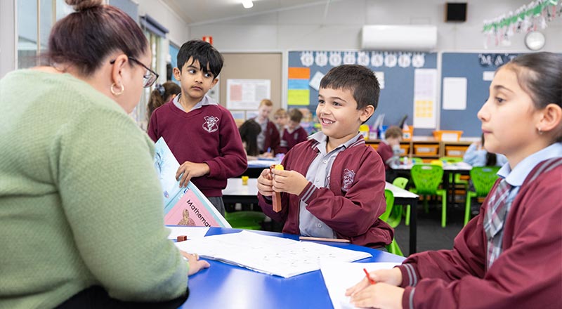 Boy working on maths, being assisted by teacher