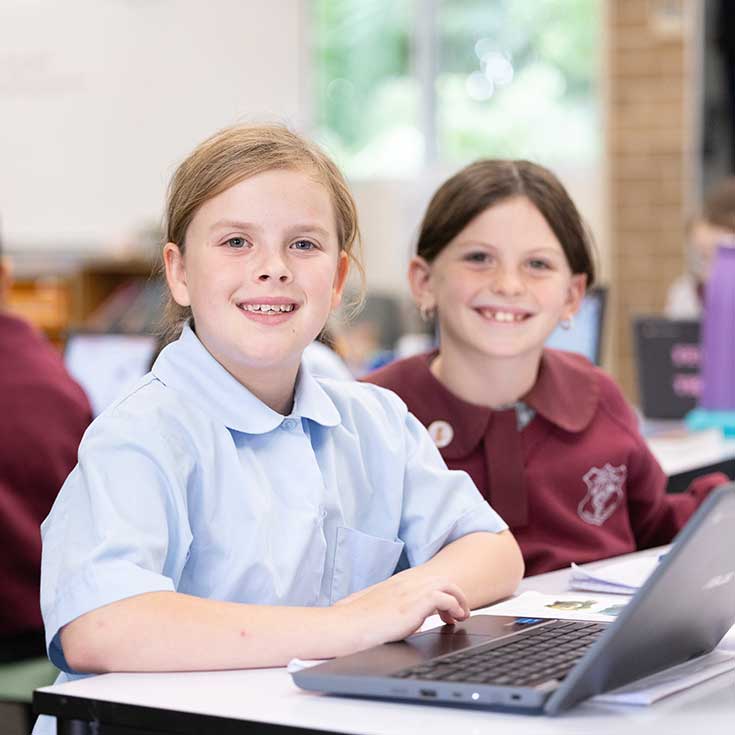 Two students, sharing a laptop