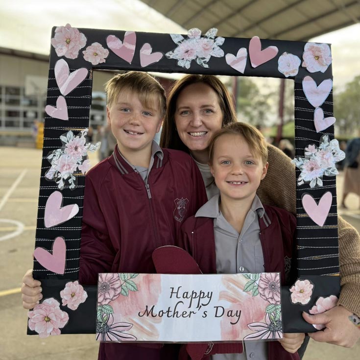 Mother and sons holding a banner that reads 'Happy Mother's Day'. Photographed on Chisholm Bligh Park playground.